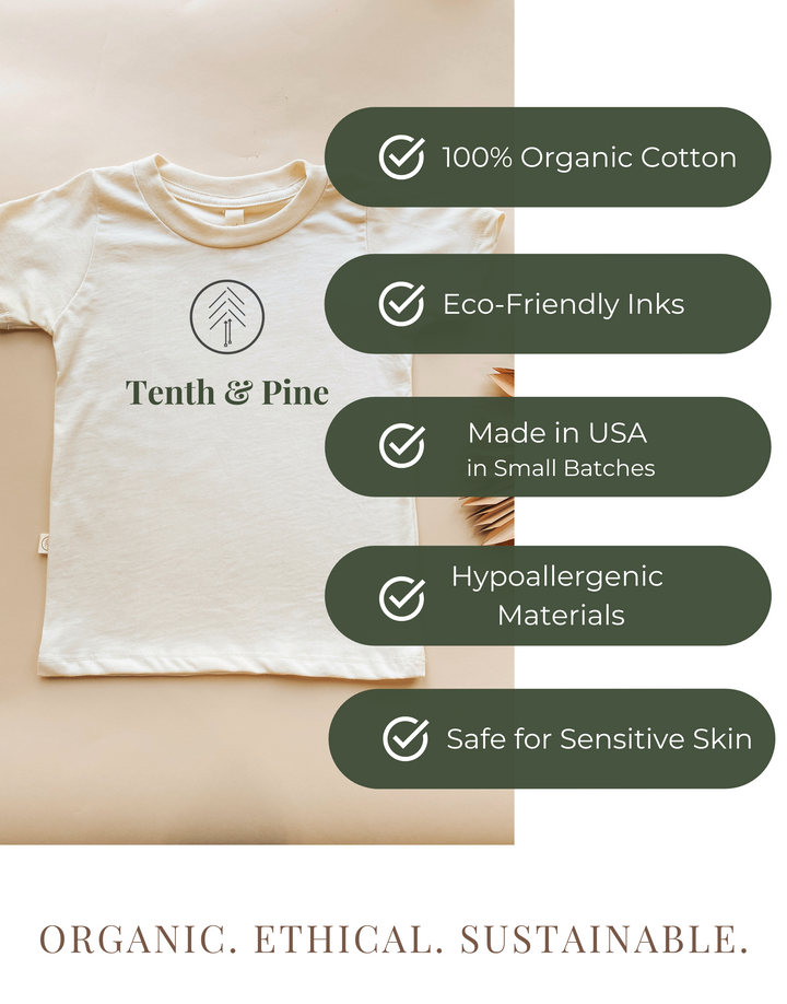 Cream kids t-shirt flat lay with badges: 100% organic cotton, eco inks, hypoallergenic.