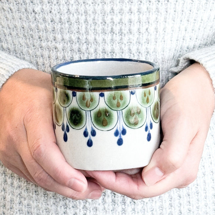 Stoneware cup with green and blue raindrop pattern, white body, glossy blue rim.