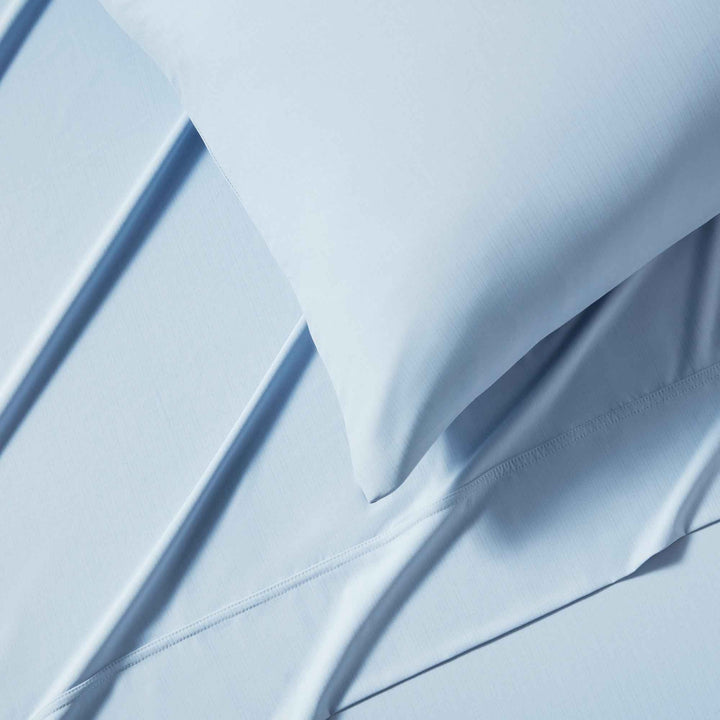 Light blue fitted sheet edge with stitched seam and folded corner