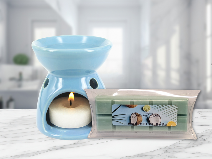 Blue ceramic wax warmer with a lit flame and a clear-wrapped wax melt bar