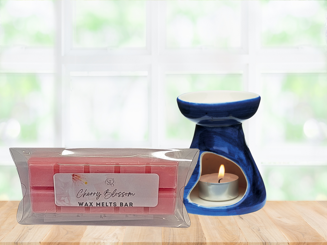 Blue ceramic wax warmer with lit tealight beside clear-wrapped cherry blossom wax melt bar