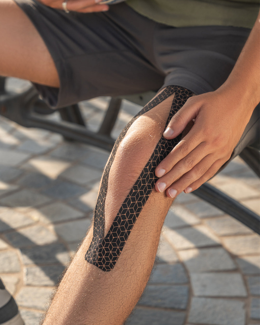 Copper kinesiology tape applied to shin in dark honeycomb hex pattern