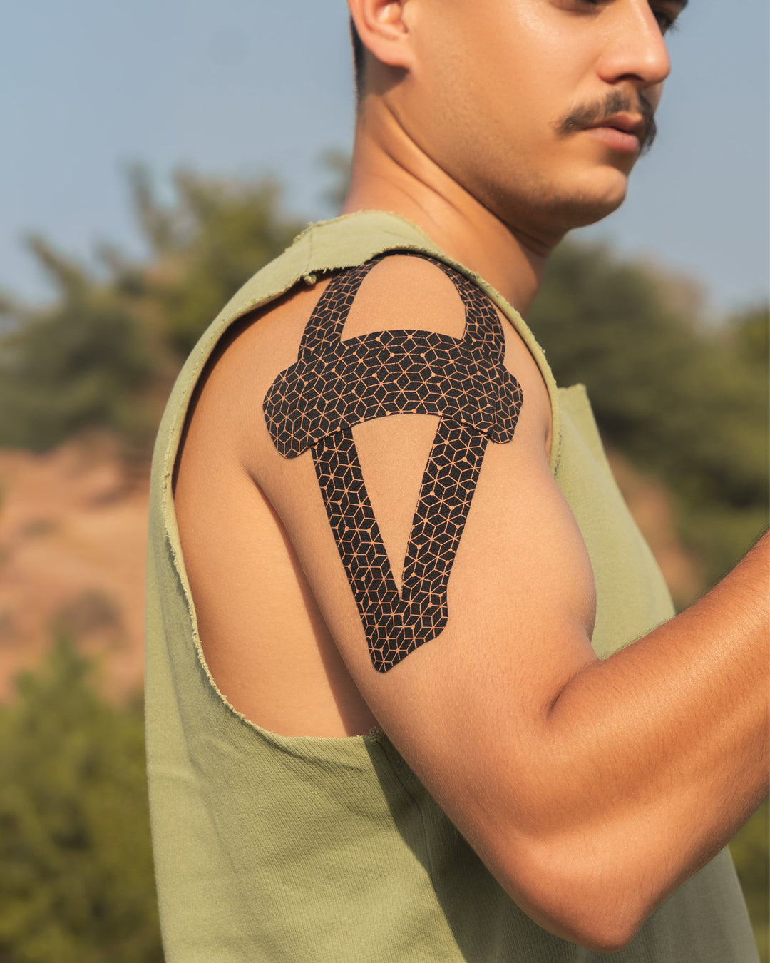 Copper kinesiology tape applied on upper shoulder in dark honeycomb pattern