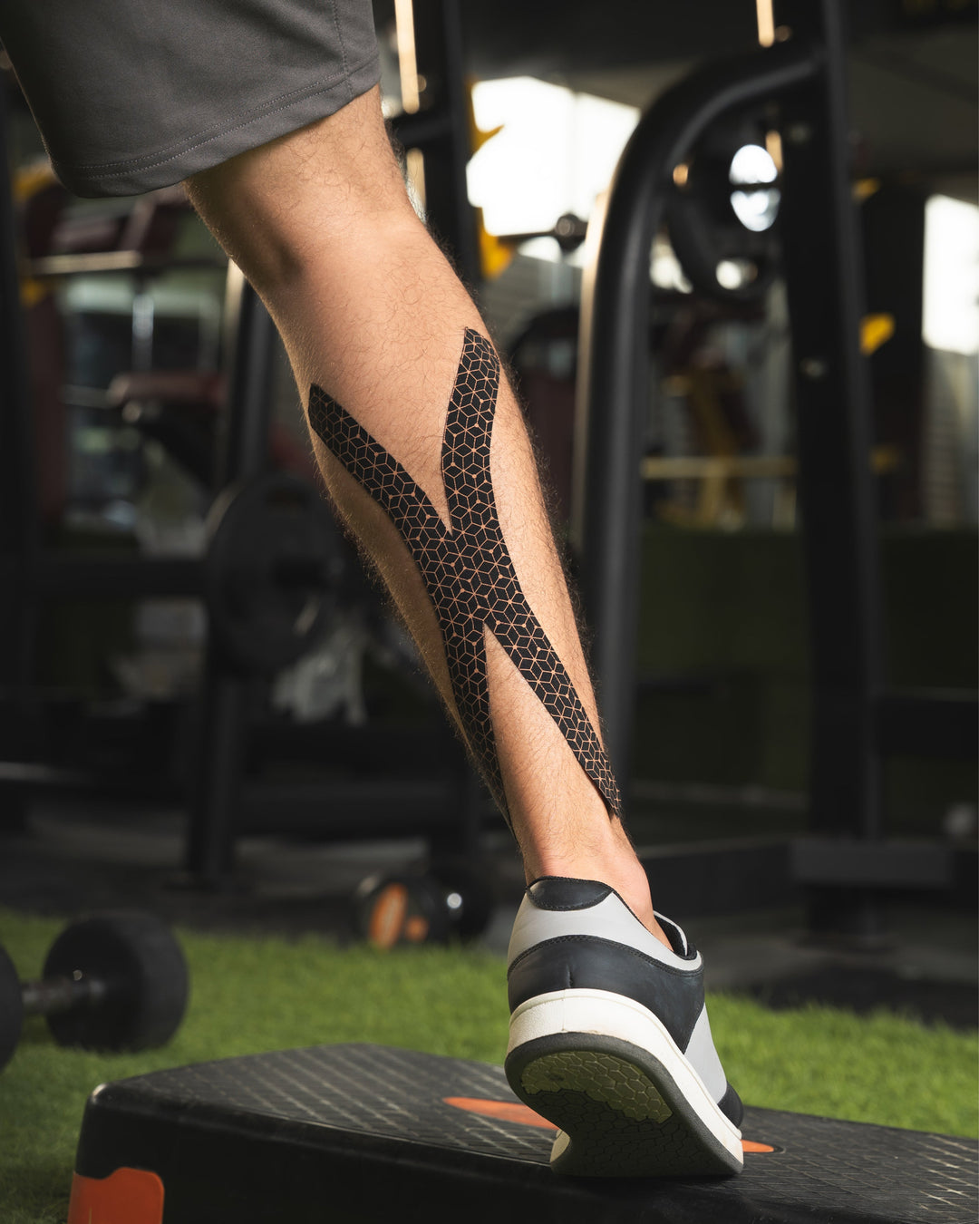 Copper kinesiology tape strips applied to lower leg and ankle, dark mesh pattern