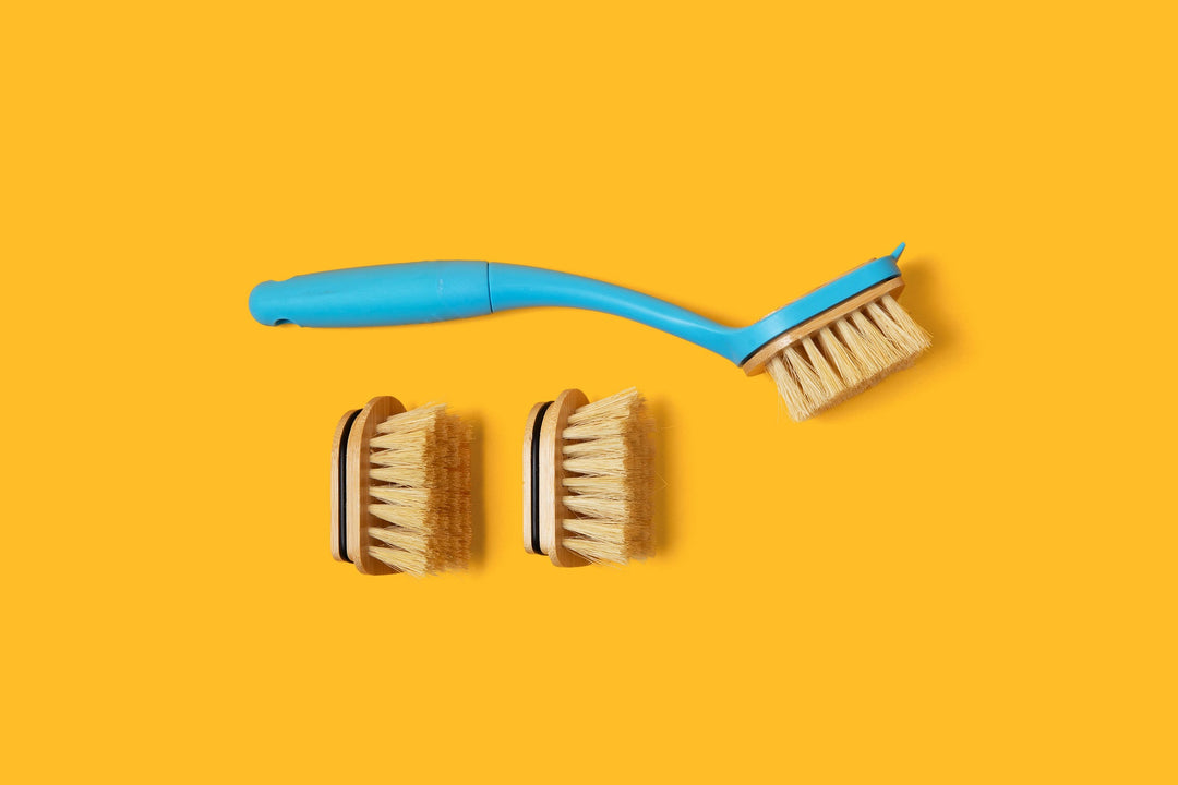 Dish brush and two spare replaceable bristle heads arranged on a bright background