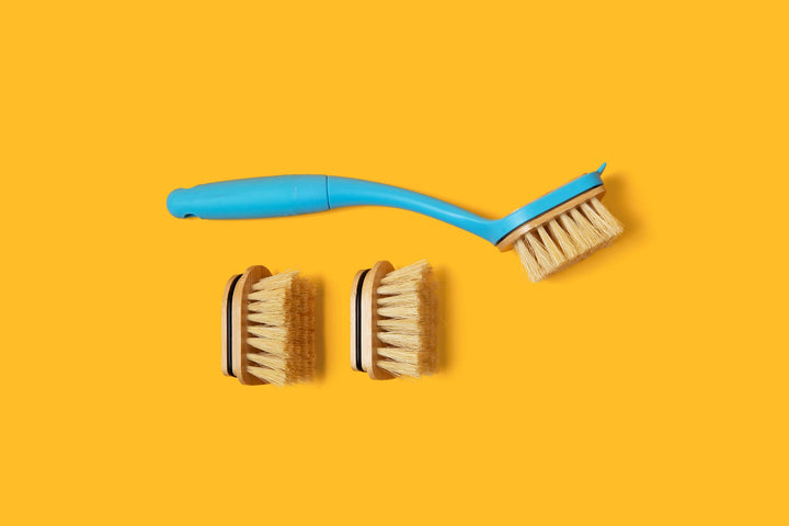 Dish brush and two spare replaceable bristle heads arranged on a bright background