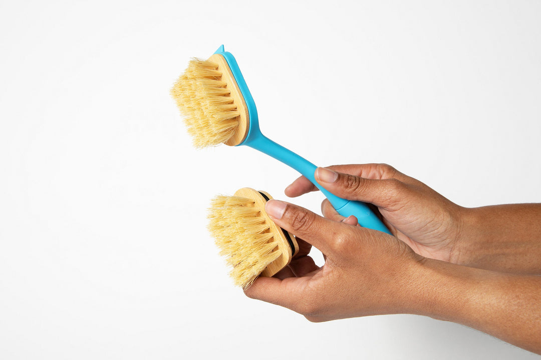 Hands comparing replaceable bristle heads for the dish brush