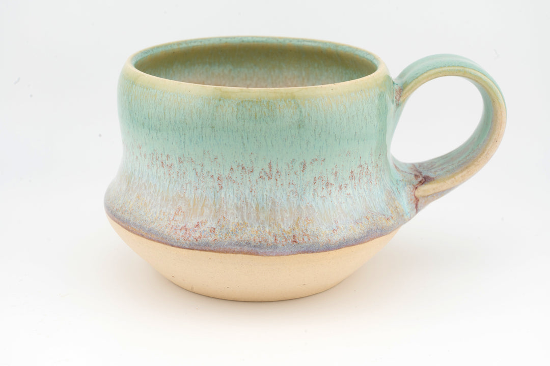 Ceramic wide mug with turquoise glaze, rounded handle, and speckled textured finish