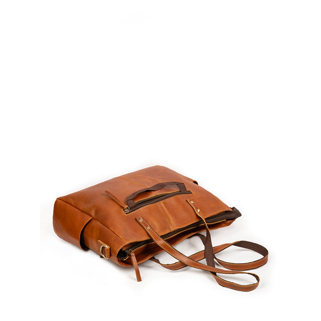 Tan leather tote bag laid flat with adjustable shoulder strap and front pocket