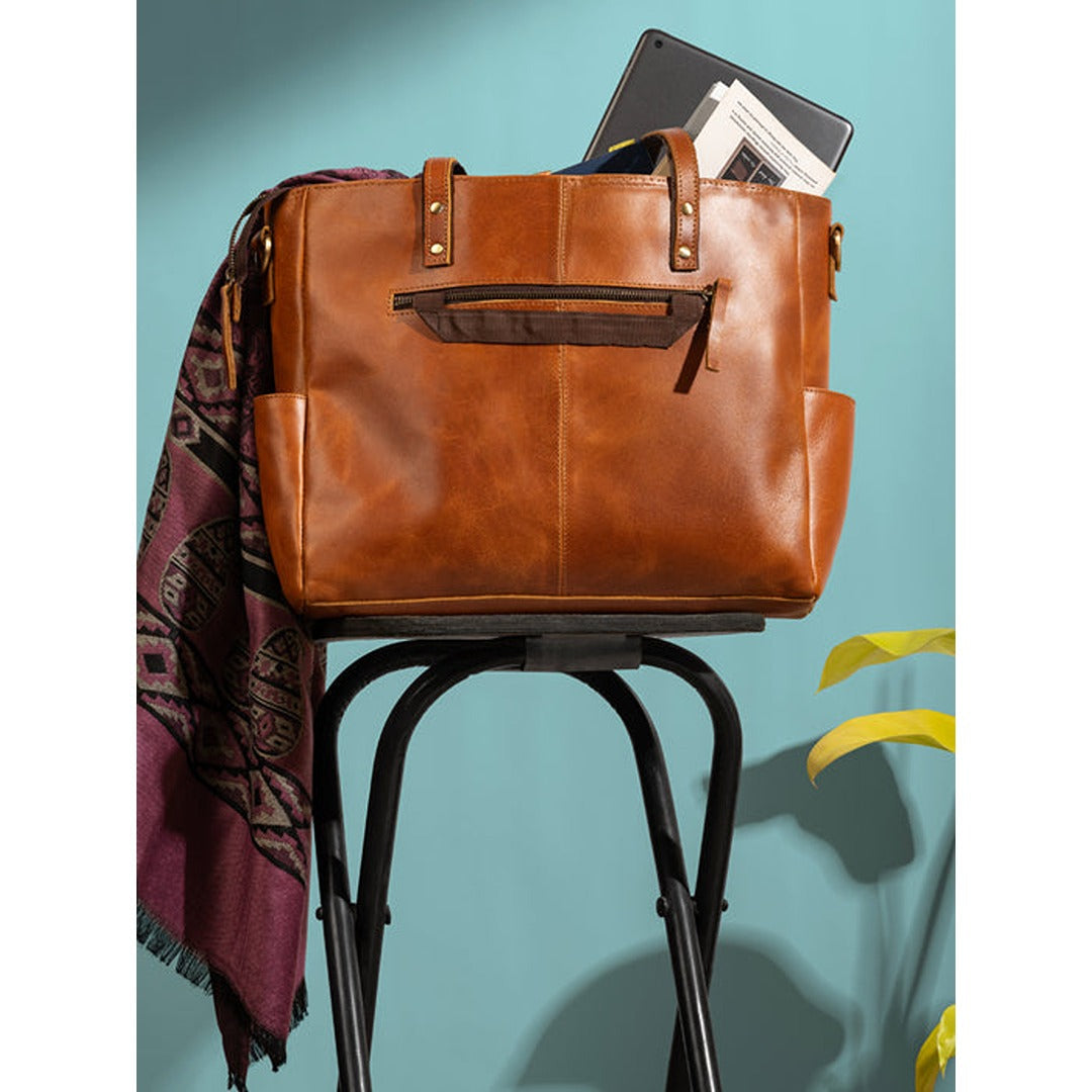 Tan leather tote bag on stroller with side pocket and metal handle hardware