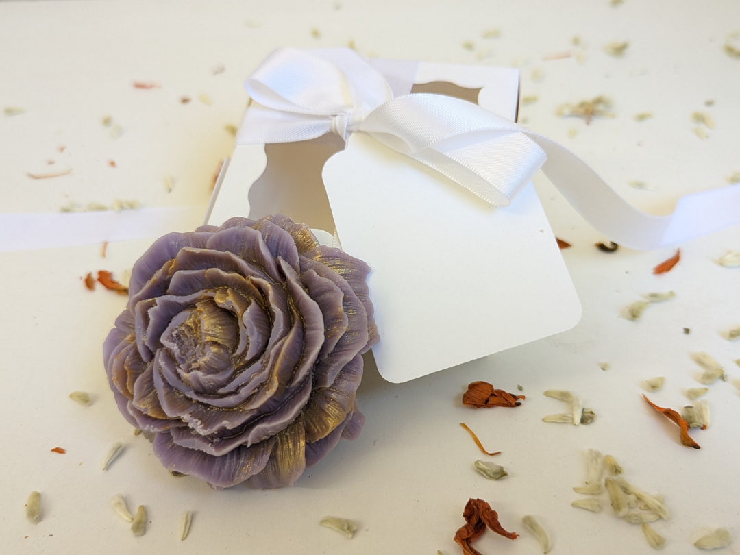Purple wax flower freshener with bow and gift tag on a light background
