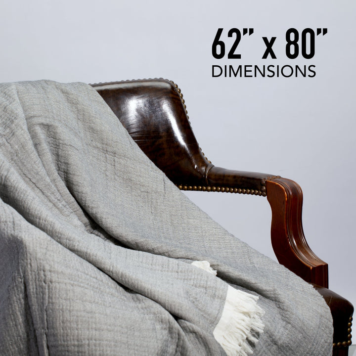 Grey muslin throw blanket draped over a chair, fringed ends