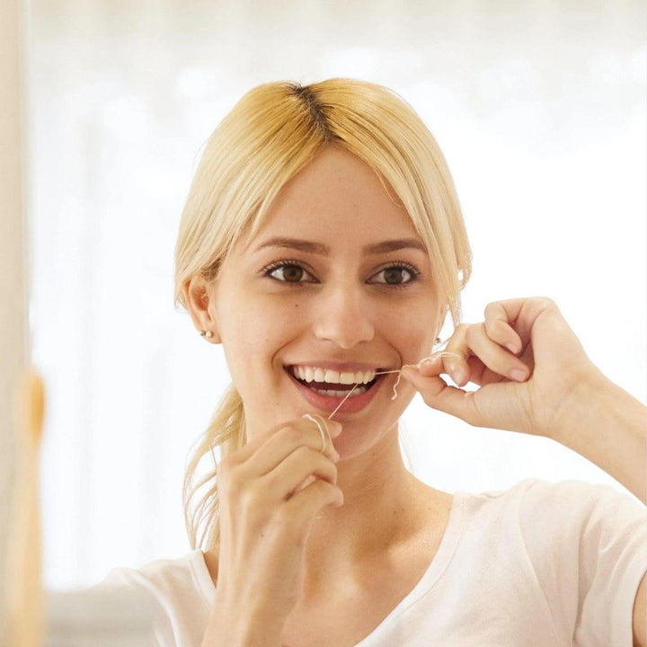 Person using dental floss with a white floss strand between teeth