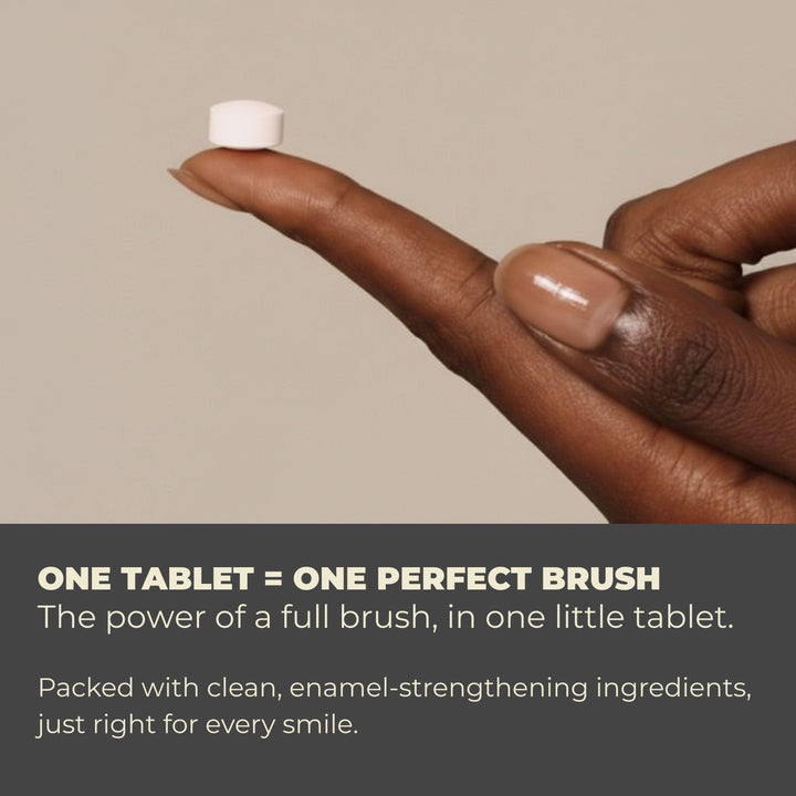 Hand holding a small white toothpaste tablet