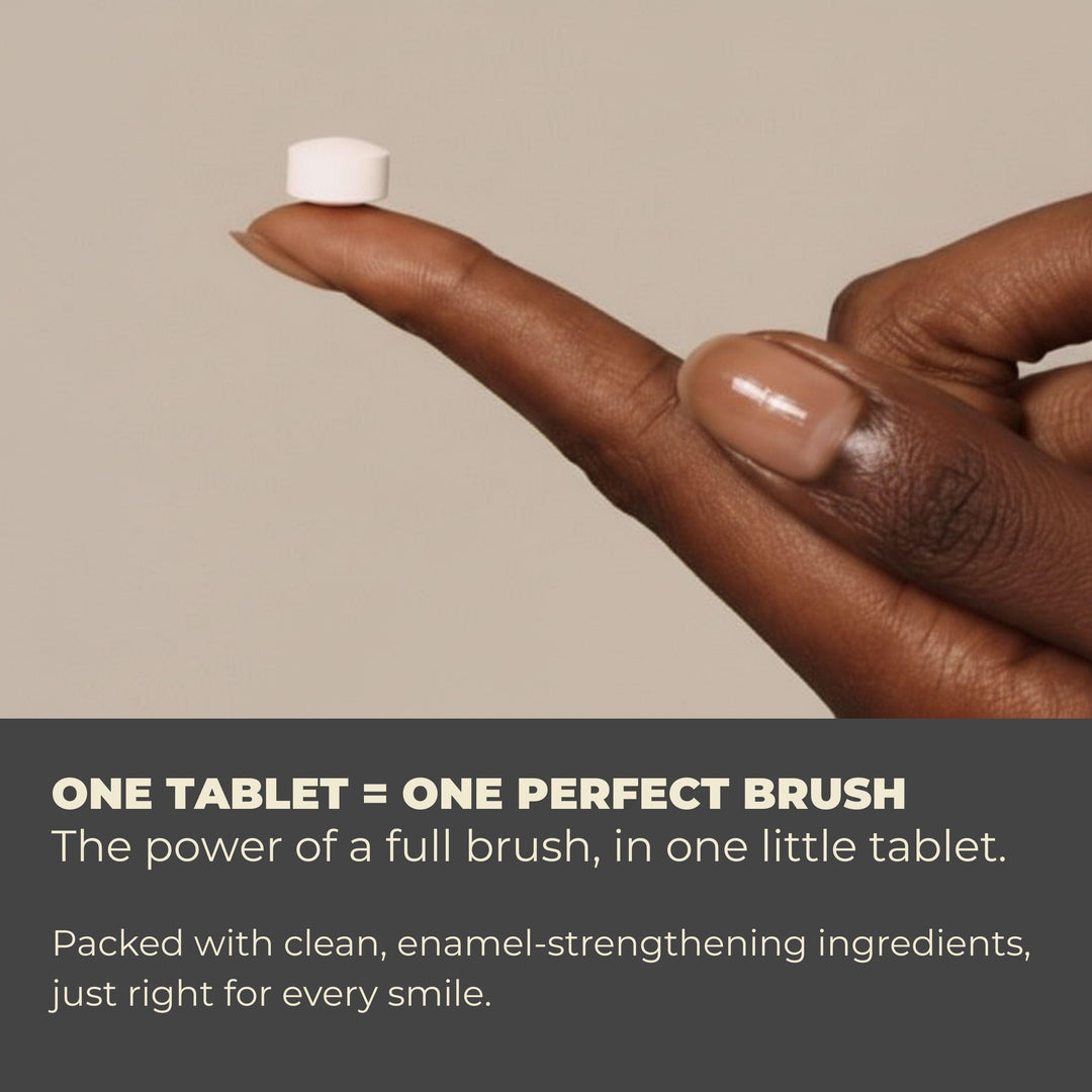 Hand holding a small white toothpaste tablet above an open palm