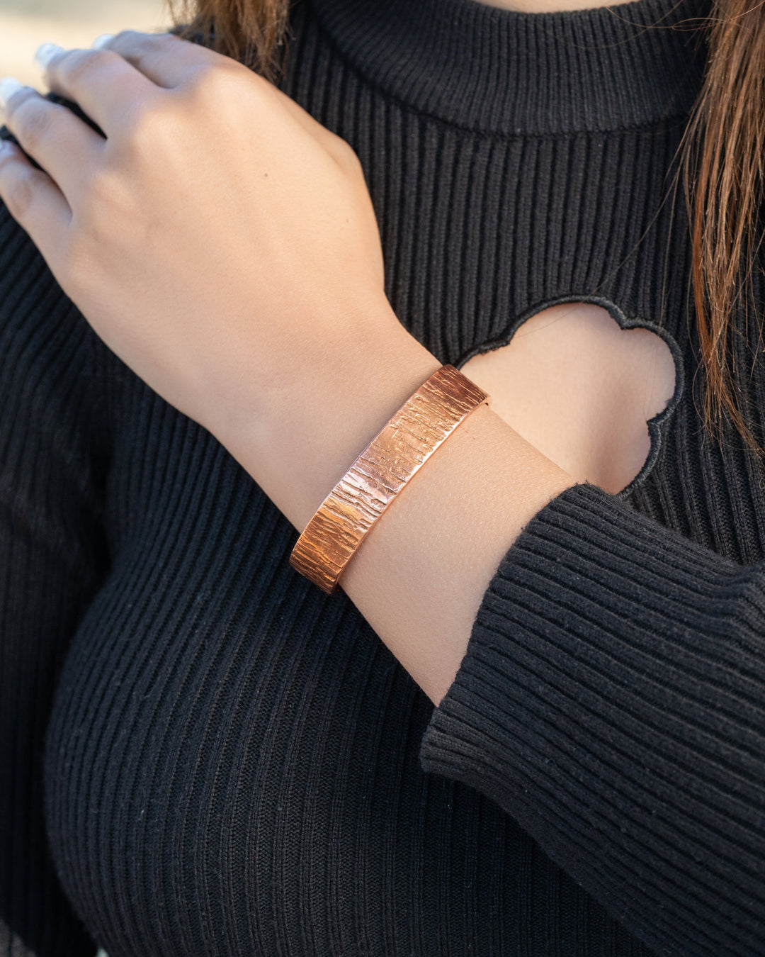 Copper cuff bracelet on wrist, textured hammered finish with wide cuff profile.