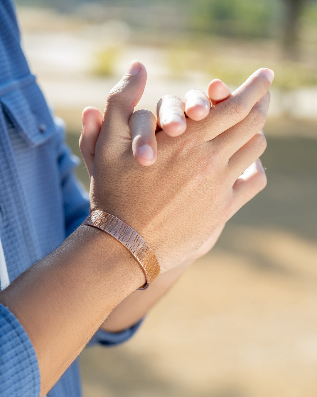 Copper cuff bracelet worn on wrist outdoors, hammered texture wide cuff.
