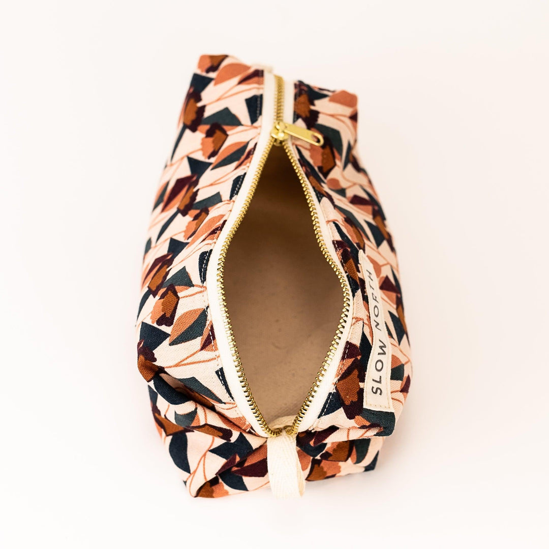 Small travel pouch with blush, navy, and brown geometric print; gold zipper