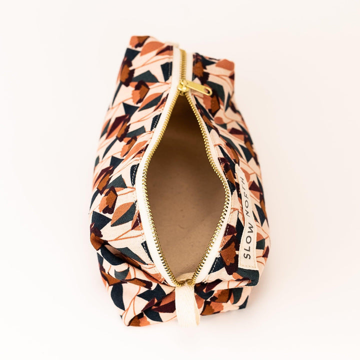 Small travel pouch with blush, navy, and brown geometric print; gold zipper