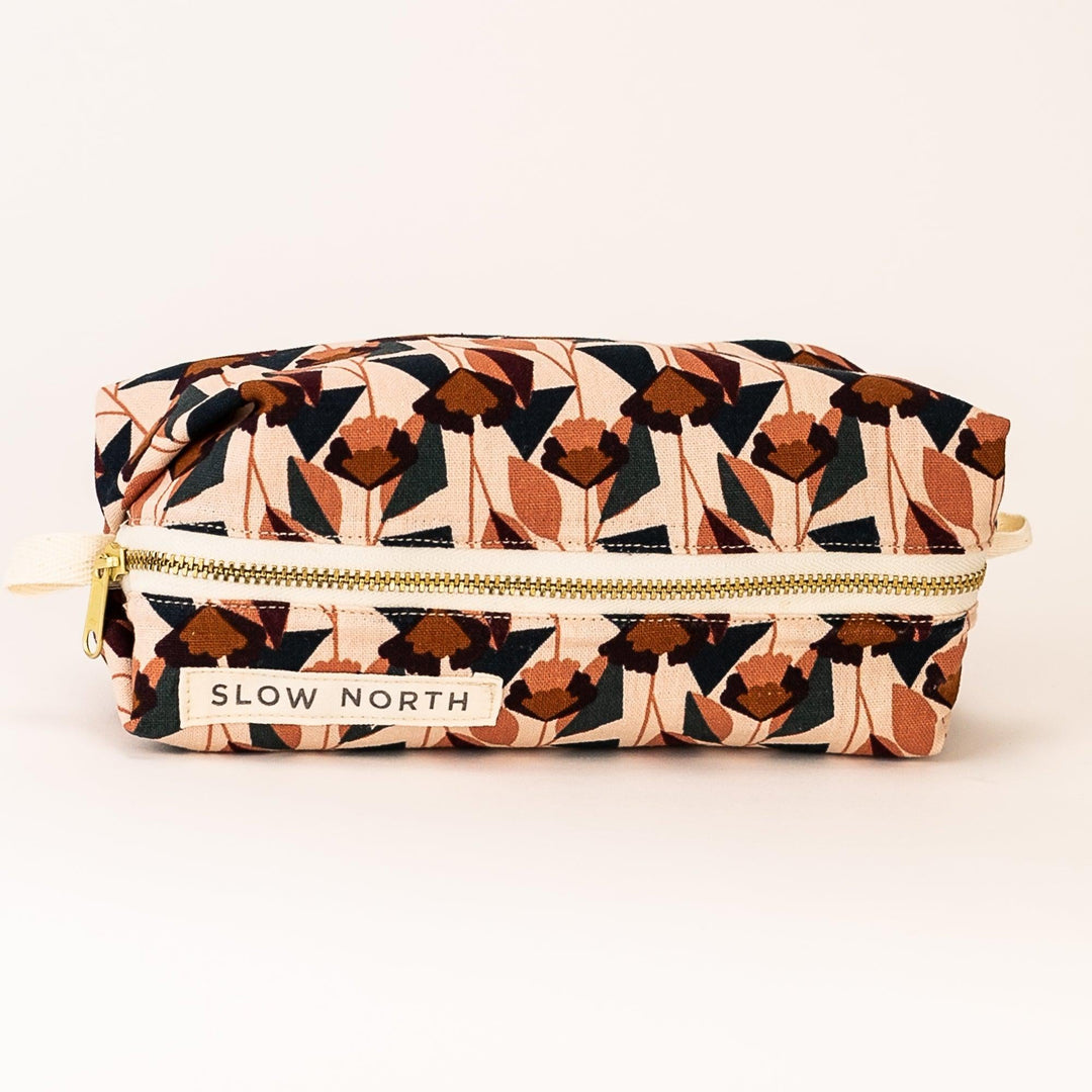 Geometric blush travel pouch with gold zipper and “SLOW NORTH” front patch