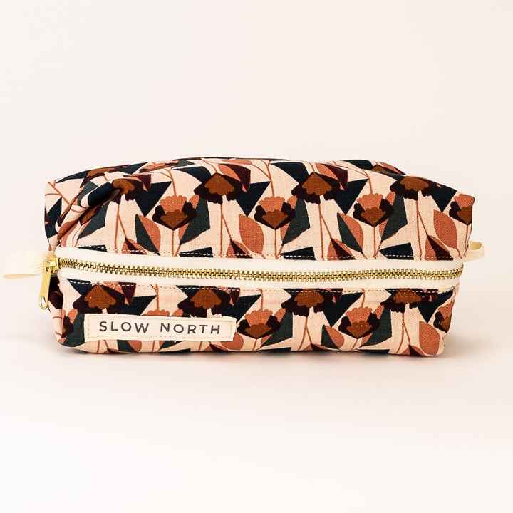 Geometric blush travel pouch with gold zipper and “SLOW NORTH” front patch