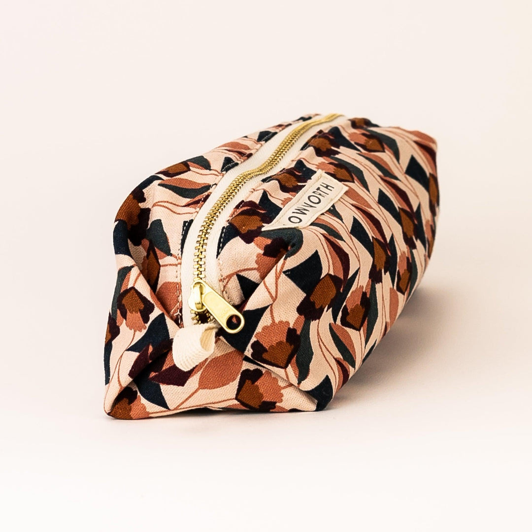 Side view of blush and navy geometric travel pouch with gold zipper pull