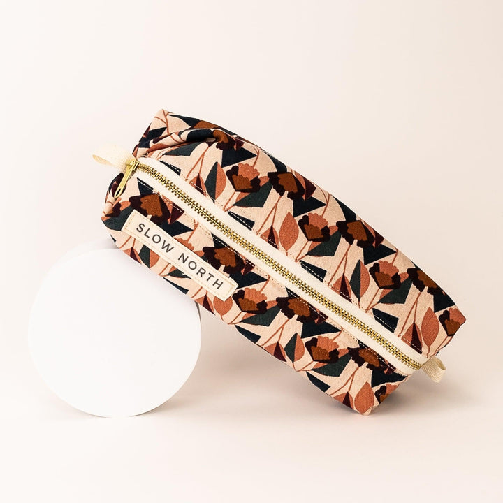 Front-side view of blush travel pouch with gold zipper and fabric wrist strap