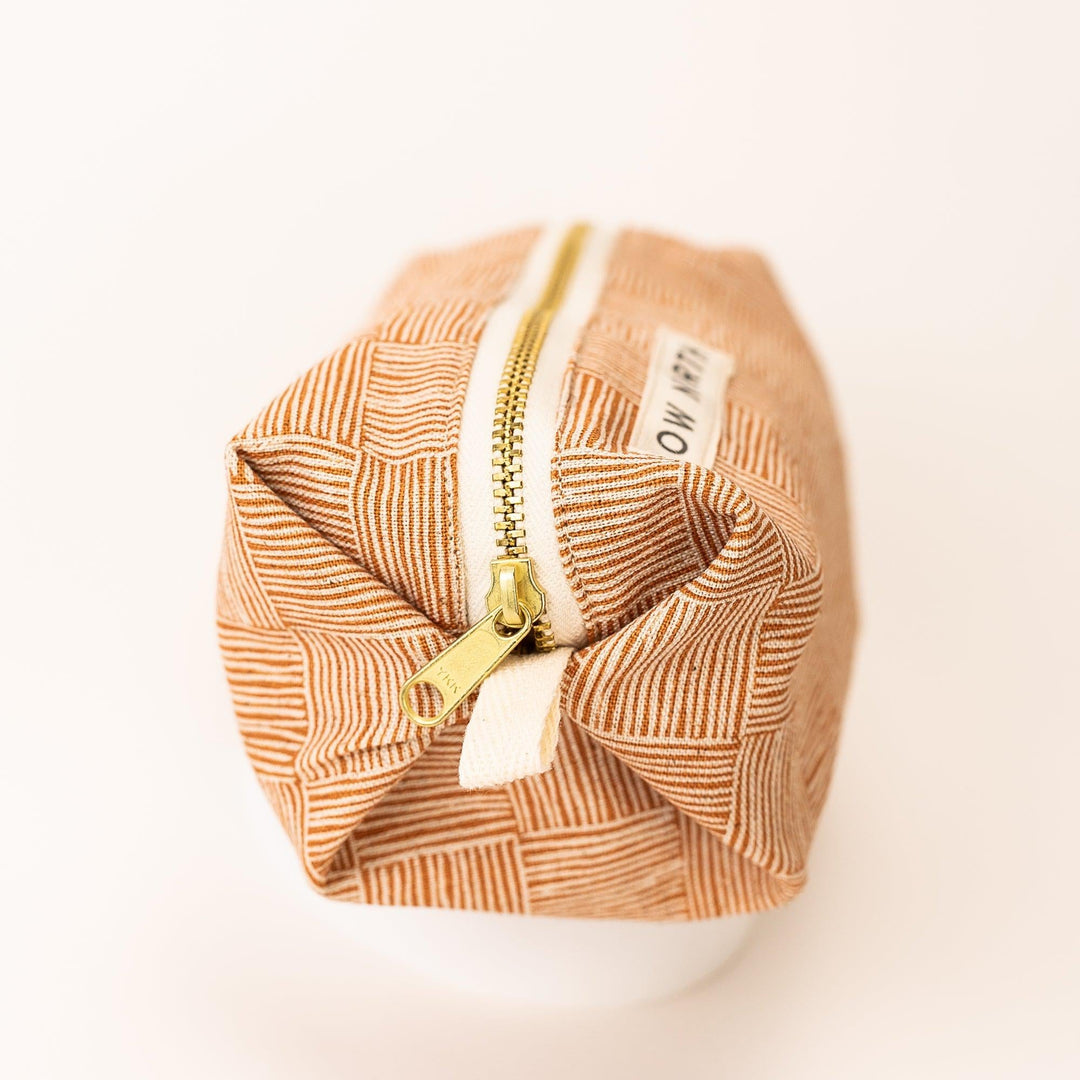 Close-up of copper patterned travel pouch with gold zipper pulls and stitched fabric lining.