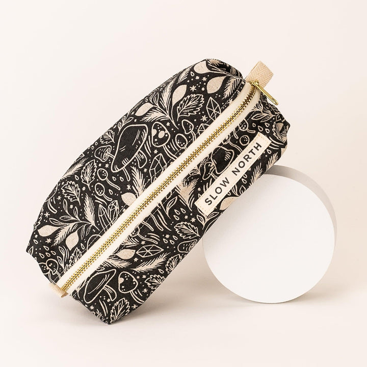 Black patterned pouch with gold zipper, cream tassel pull and “SLOW NORTH” tag