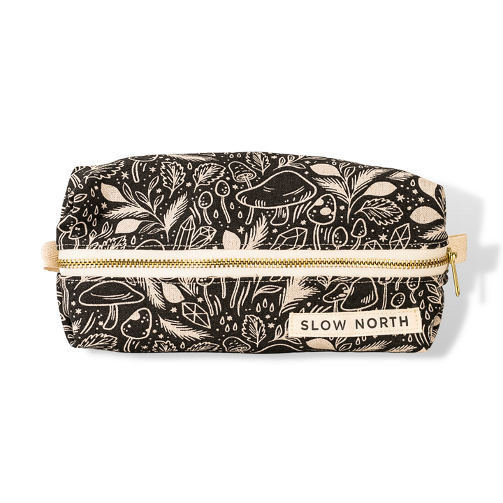 Black fabric travel pouch with gold zipper and “SLOW NORTH” label