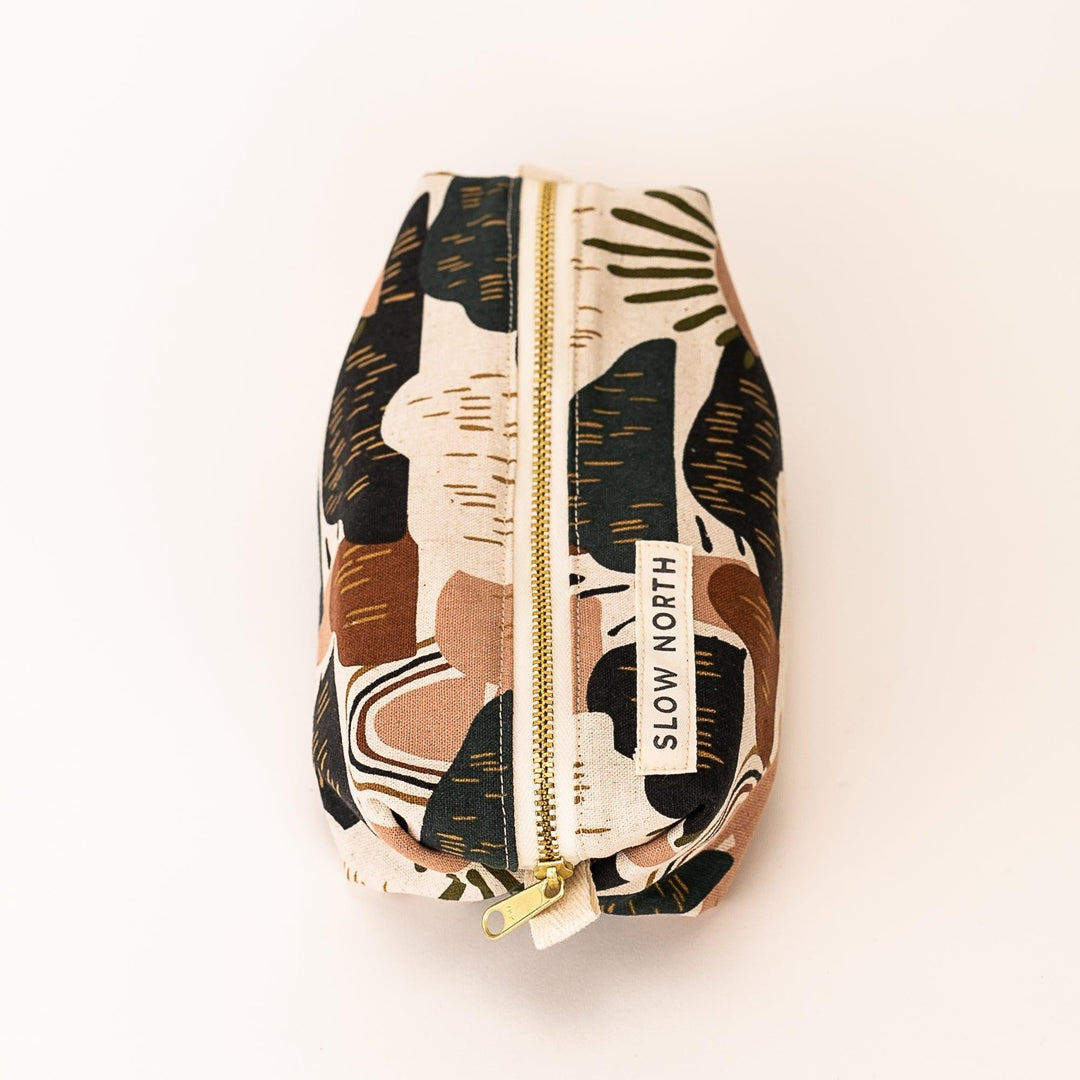 Side view of desert-print zipper pouch in tan and black with gold zipper and tag