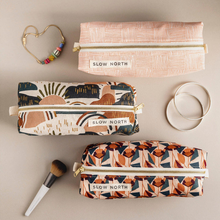 Set of three patterned travel pouches with gold zippers and SLOW NORTH labels
