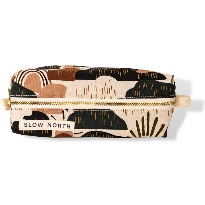 Zippered travel pouch with desert-pattern fabric in tan, black, and cream; front label