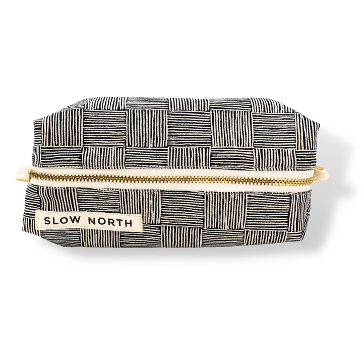 Black-and-white patterned travel pouch, gold zipper, SLOW NORTH label