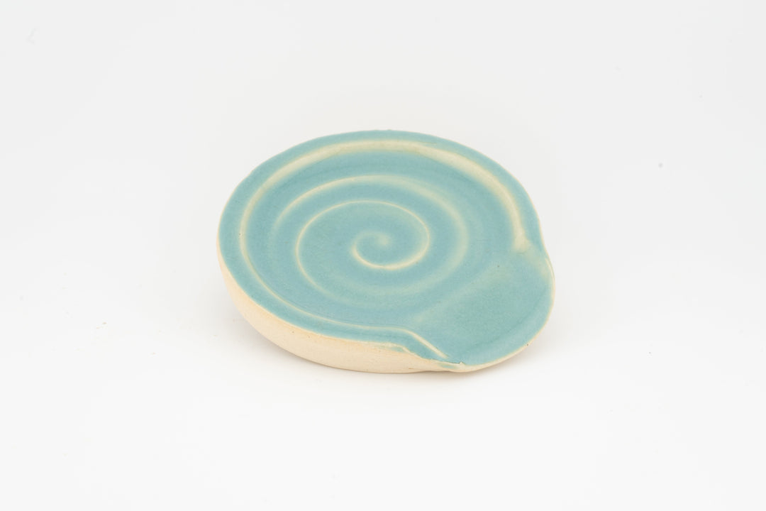 Light blue ceramic spoon rest with subtle swirl pattern and curved rim