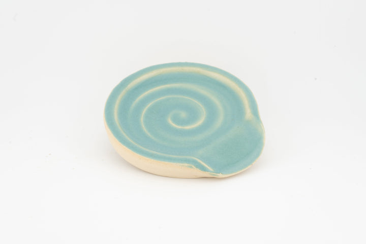 Light blue ceramic spoon rest with subtle swirl pattern and curved rim