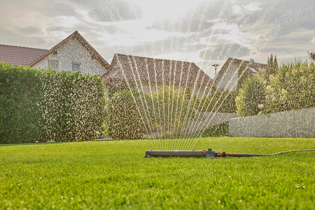 Oscillating sprinkler spraying a fan-shaped water stream over lawn