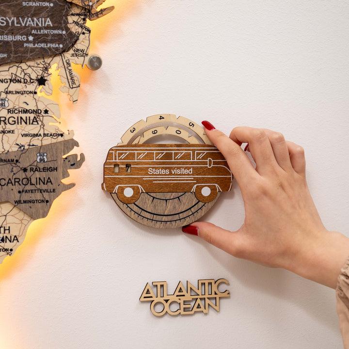 Hand attaching a wooden car-shaped USA travel tracker marked “States visited”.