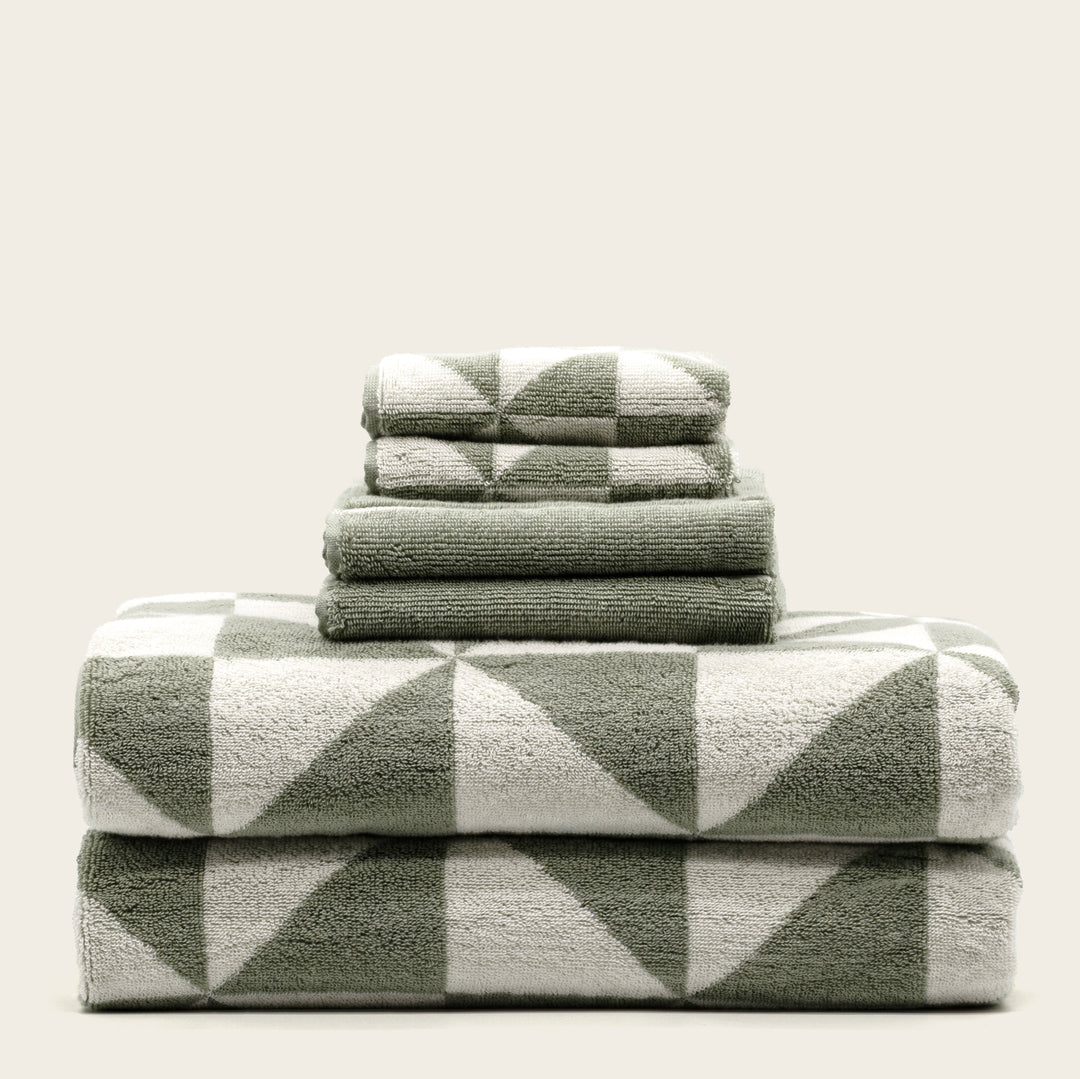 Green-and-ecru cotton towels with geometric check pattern, folded stack of four.