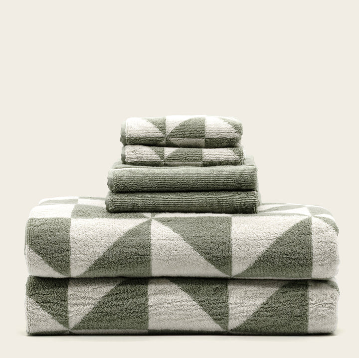 Green-and-ecru cotton towels with geometric check pattern, folded stack of four.
