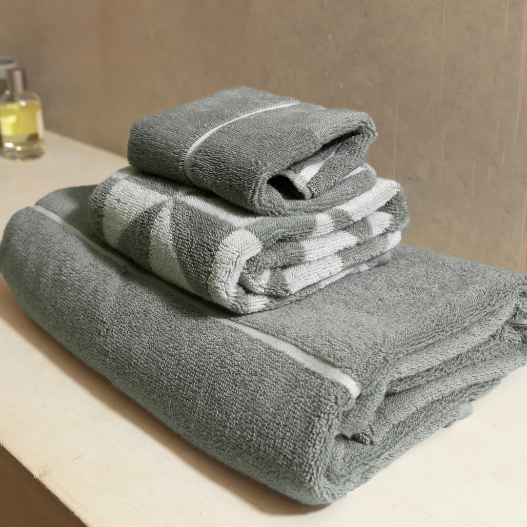 Stacked sage-green cotton towels with white striped diamond pattern