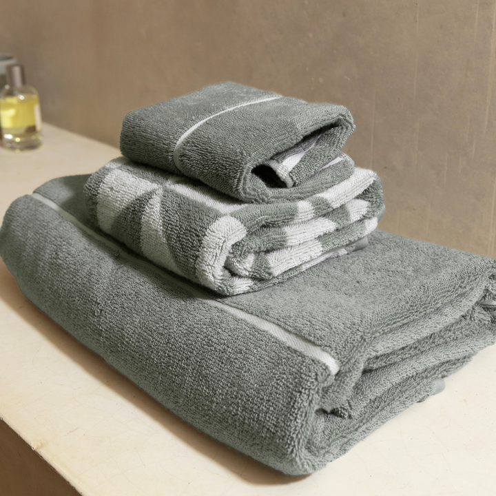 Stacked sage-green cotton towels with white striped diamond pattern