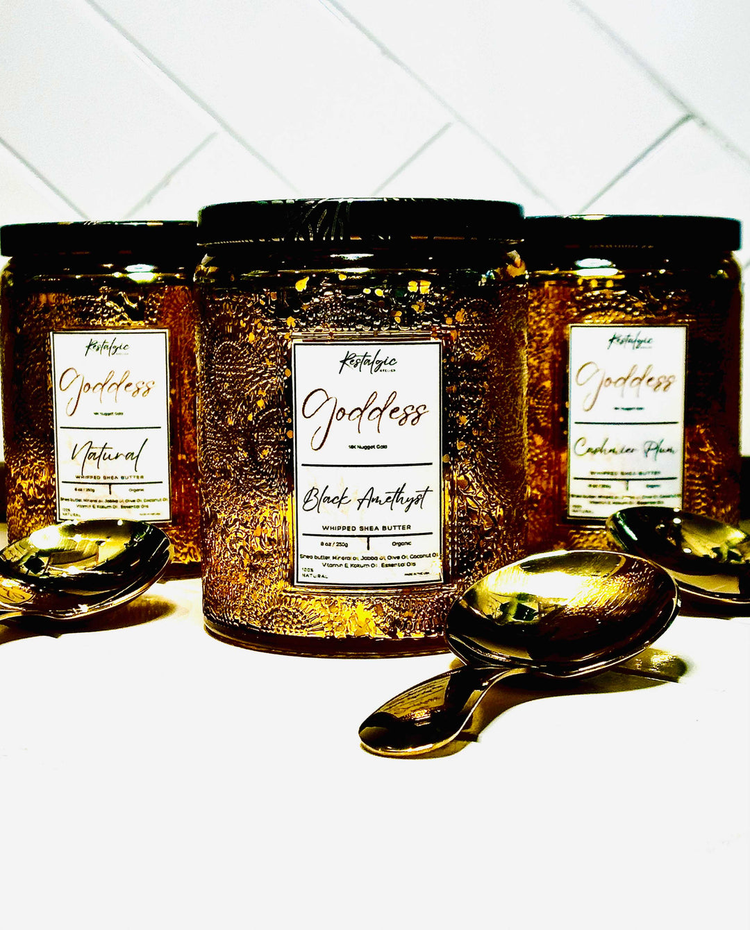 Gold body butter jar with black lid and gold spoon, amber label design in view