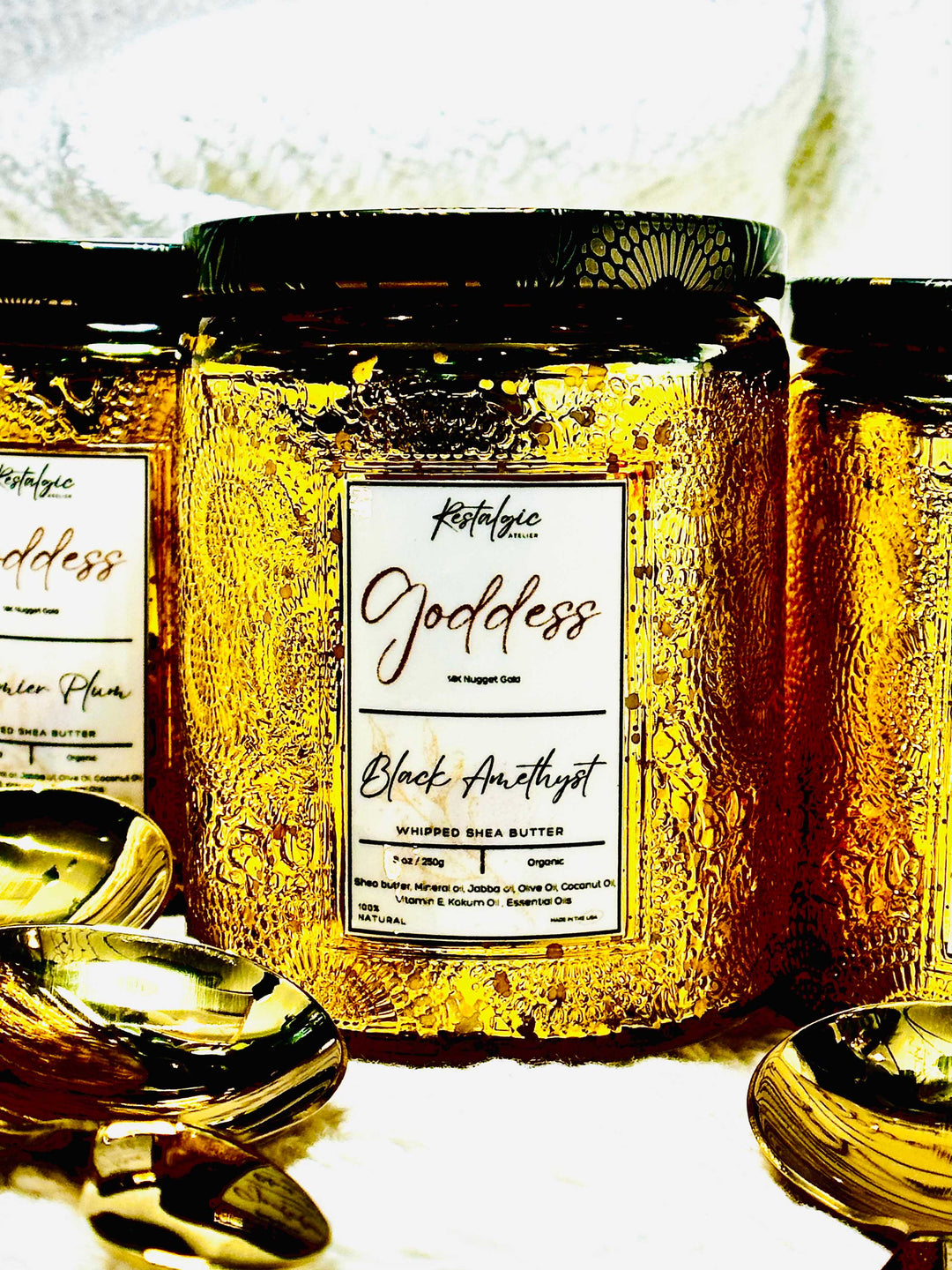 Amber gold body butter jar with black lid and gold spoon, label reads “Black Amethyst”