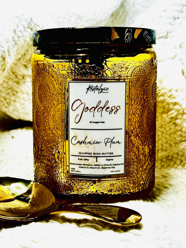 Amber body butter jar with black lid and gold spoon, label reads “Obsidian Plum”