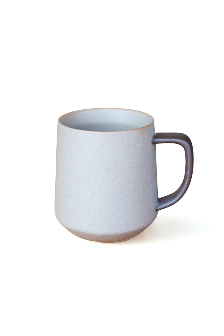 Two-tone ceramic mug with dark handle and light speckled body, rounded shape