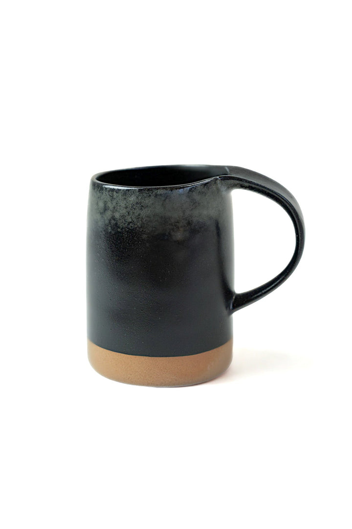 Black stoneware-style mug with tan base and curved side handle