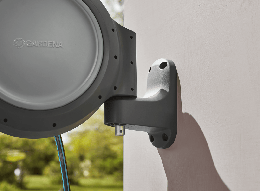 Close-up of retractable hose reel wall bracket holding gray reel with blue hose