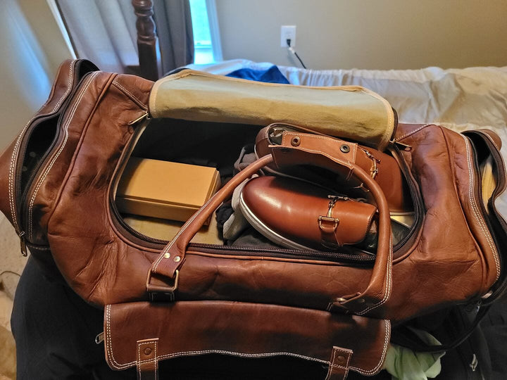Brown leather duffel bag open with toiletries and organizer pouch inside