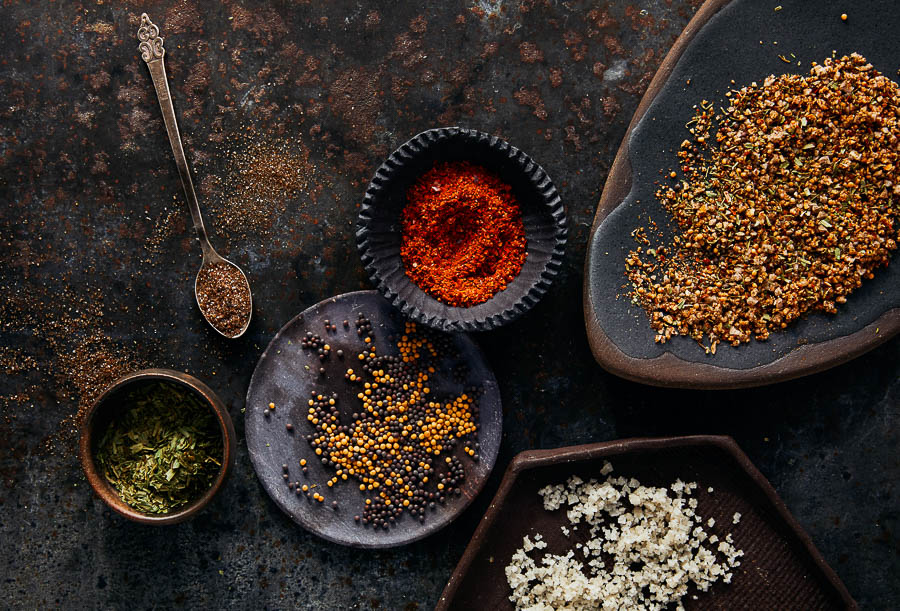 Spice blend mix in bowls and spoons, fine yellow, orange, and dark spices
